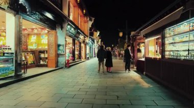 HANGZHOU, ÇİN 2, 2021: Geceleri dükkanlar ve restoranlarla sokak manzarası