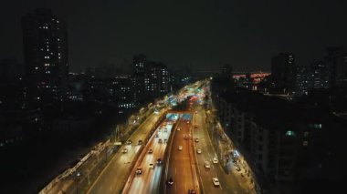 Çin 'in Jiangsu şehrinde gece vakti Nanjing şehrinde sokak trafiği olan şehir binalarının hava görüntüsü.