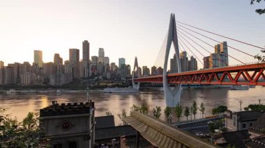 Chongqing şehrinin kentsel mimari manzarası ve Çin 'de gün batımından batımına kadar nehir üzerinde köprü.