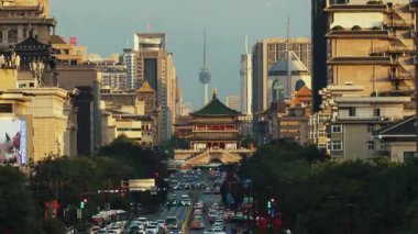 Çin 'in Şanksi kentindeki Xian şehrinde gün batımından geceye kadar trafik ve çan kulesi olan işlek caddenin hızlandırılmış görüntüsü