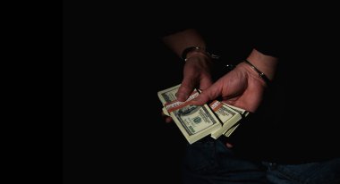 Tutuklanan adamın siyah arka plana kelepçelenmiş para ile yakalanması yolsuzluğun sembolü, yasadışı bahşişler. Boşluğu kopyala.