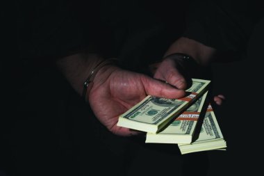 Yolsuzluk ve yasadışı bahşiş simgesi olarak elleri kelepçeli, tutuklu bir adam yakın plan.