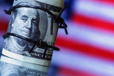 Ekonomik savaş, yaptırımlar ve ambargo kırma kavramının sembolü olarak ABD bayrağına dikenli tellere sarılı Amerikan Doları para birimini kapatın. Tasarım veya metin için boşluk kopyala.