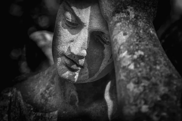Close up very ancient stone statue of man crying on the tomb for the loss family. Death, cemetery, end of human life. Horizontal image.