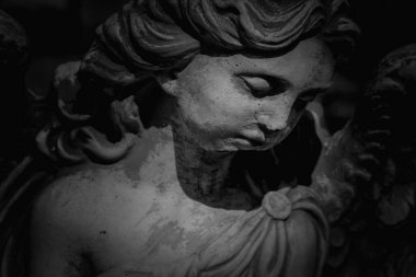 Close up black and white horizontal image of ancient statue of guardian angel.