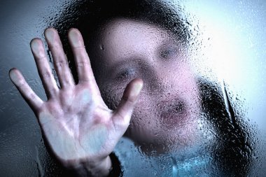 Violence, abuse, school bullying, body language concept. Portrait of beautiful female kid standing behind wet glass  and doing stop gesture.