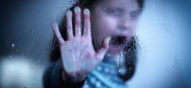 Stop violence against children. Young girl screams and making STOP gesture behind wet glass. 