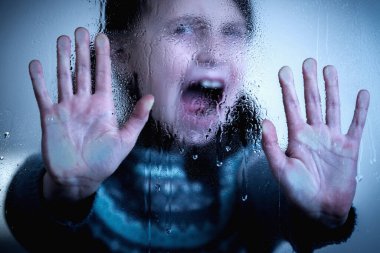 Protect children and young underage people from violence, exploitation, abuse, and neglect concept. Close up young girl say NO from behind wet glass. 