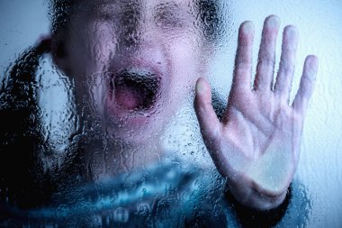 Dramatic portrait of  young kid saying NO and showing STOP with palm of the hand. Warning gesture