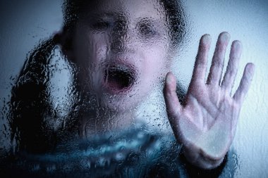 Dramatic portrait of  young kid saying NO and showing STOP with palm of the hand. Warning gesture