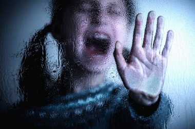 Dramatic portrait of young girl with a raised hand making a stop sign gesture. Violence, harassment and child abuse prevention concept.