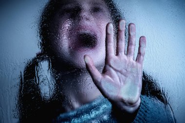 Dramatic portrait of scared young girl making NO sign, showing hand STOP gesture. Kid standing behind wet glass and says No to domestic violence, abuse, school bullying,  problem concept
