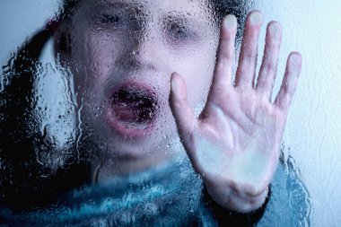 Dramatic portrait of young child girl says NO to bullying with hand stop gesture