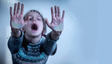 Portrait of up upset little girl protesting behind wet glass. Horizontal image. Copy space.