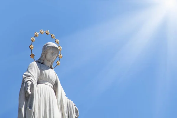 Virgin Mary against blue sky. An ancient statue
