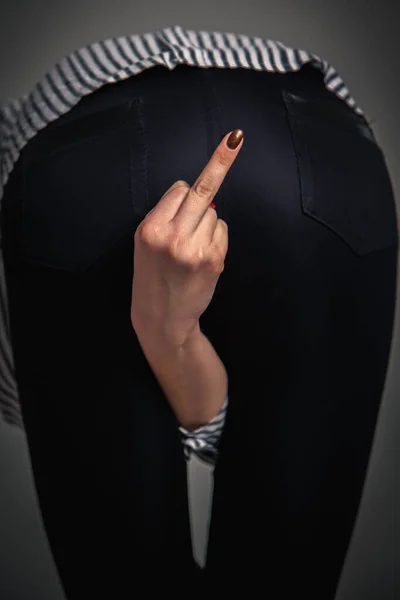 Psychological photography: hidden aggression and assertiveness of a person. Woman show middle finger sign between her legs.