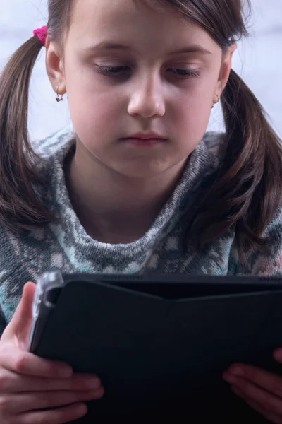 Online education concept. Portrait of happy beautiful young girl using tablet for education. Positive child girl using modern technologies. Vertical image.