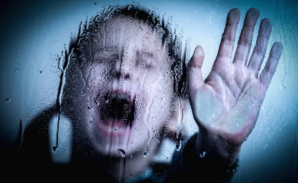 Violence, abuse, school bullying, body language concept. Beautiful female kid standing behind wet glass  and doing stop gesture.