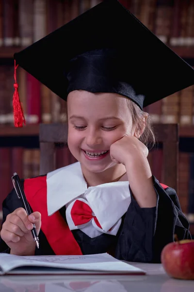 Education, school, knowledge and people concept. Happy beautiful child girl  in graduation cap learning in library. Vertical image.