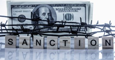 Ekonomik savaş, yaptırımlar ve ambargo kırma kavramı. Dikenli tellere sarılı Amerikan Doları. Yatay resim.
