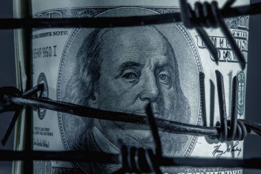 Ekonomik savaş, yaptırımlar ve ambargo kırma kavramı. Amerika Birleşik Devletleri bayrağına karşı dikenli tellere sarılı Amerikan Doları banknotlarını kapatın. Seçici odak.