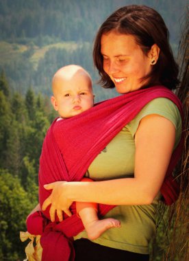 Anne ve çocuğu açık havada asılıydı. Anne ve bebek güneşli ışıklarda eğleniyorlar. Aile birlikte eğleniyor. Mutlu çocukluk kavramı. Dikey resim.