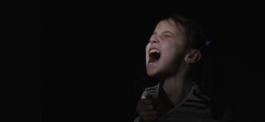 Kavramsal görüntü: çocuklarda acı. Gergin ve aşırı heyecanlı genç kızın psikolojik portresi çığlık atıyor ve tişörtü yırtmak istiyor. Boşluğu kopyala.