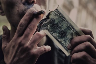 100 dolarlık banknotla puro yakan genç bir adamın portresi. 
