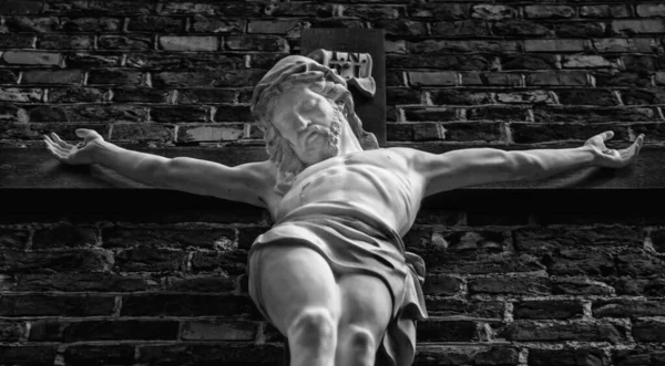 耶稣被钉十字架的古老雕像的底部视图 有选择地专注于雕塑的表面 黑白图像 — 图库照片