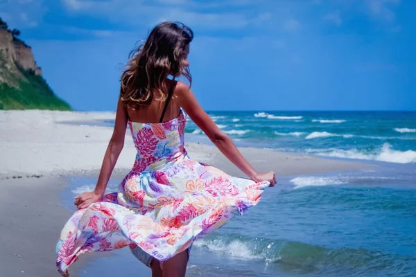 stock image Portrait of young beautiful slim woman wearing in a dress walking on the seashore in the sunrays. Holiday, sommer travel, rest concept. 