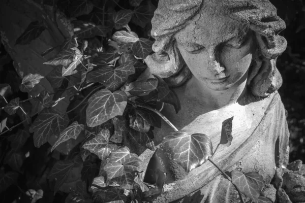Sad Angel. Fragment of ancient statue. Horizontal image. Black and white image.