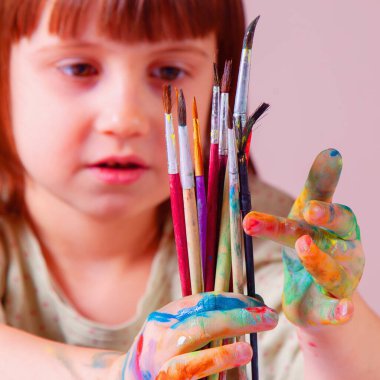 Fırça tutan boyalı elleri olan güzel bir kızın portresi. Sanat, çocukluk, öğrenme ve yaratıcılık kavramı. 