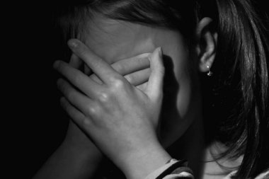 Psikolojik yaralanmalar, çocukların endişeleri ve korkuları, kayıp çocukluk. Üzgün, üzgün ve mutsuz küçük kız kendini yalnız hissediyor. Ağlıyor, elleriyle yüzünü örtüyor..