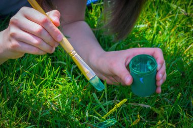 Obsesif kompulsif bozukluk (obsesif kompulsif bozukluk) genç güzel bir kızın portresi yeterince yeşil olmadığı için çimleri yeşile boyar. Yatay resim.