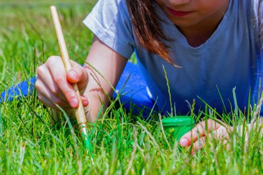 Obsesif-kompulsif bozukluk (OCD) kavramı. Genç güzel kız çimleri yeterince yeşil olmadığı için yeşile boyar. Yatay resim.