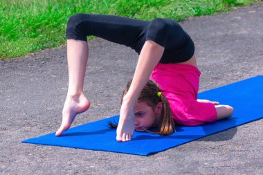 Yoga zamanı, sağlık konsepti. Açık havada yoga yapan ve spor yapan genç ve çekici bir kızın portresi..