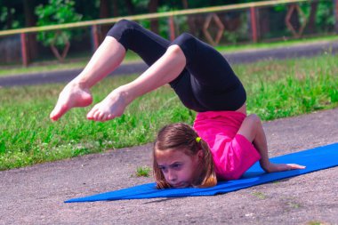 Yoga zamanı, sağlık konsepti. Açık havada yoga yapan ve spor yapan genç ve çekici bir kızın portresi. Sağlıklı yaşam tarzı kavramı. 