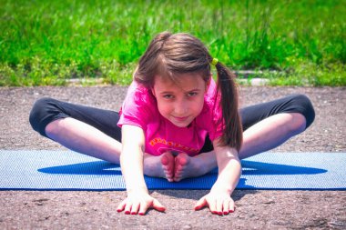Genç sportif çekici kız dışarıda yoga yapıyor. Sağlıklı yaşam tarzı ve akıl sağlığı konsepti. Yatay resim.