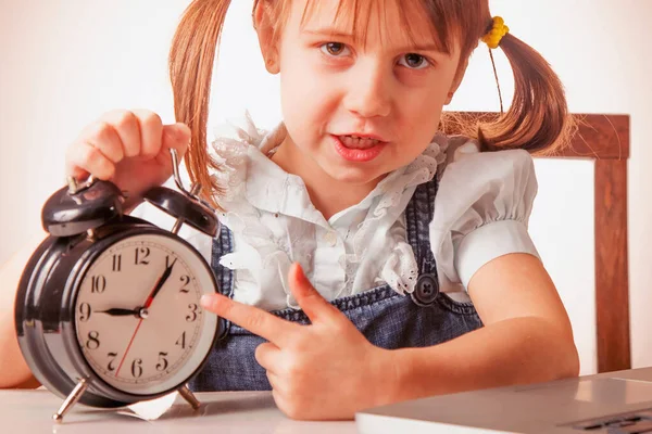 Portrait of young attractive business child girl pointing on clock with finger as if she want to say: Don\'t be late! It\'s time to work!