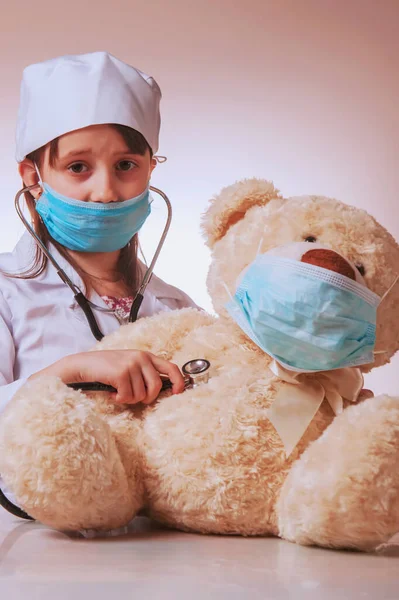 小さなかわいい悲しい子の医者で保護顔マスクチェックボディのおもちゃテディベアによる聴診器 ウイルス病はペットの概念のための危険な許可である 視覚的なイメージ — ストック写真