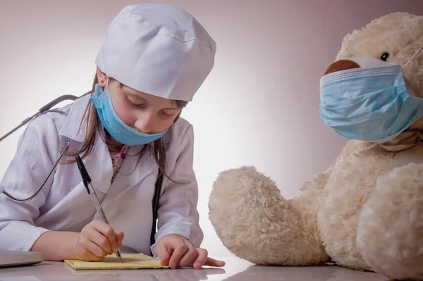 Маленькая Грустная Девочка Доктор Защитной Маске Заполняющая Бумаги Пациента Медведя — стоковое фото