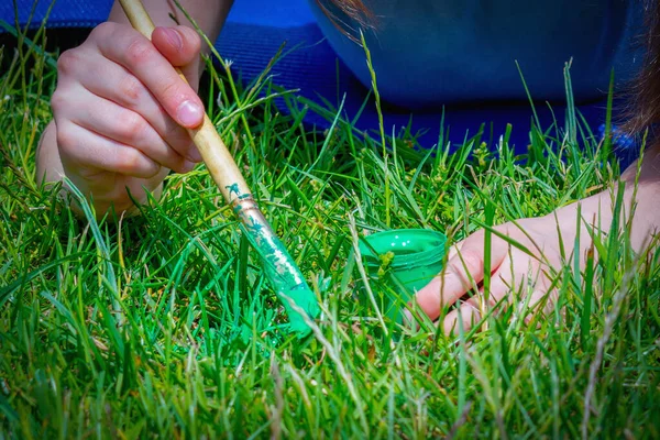 stock image Conceptual image: Obsessive-compulsive disorder (OCD). Portrait of young beautiful girl paints the grass green because it is not green enough. Horizontal image.