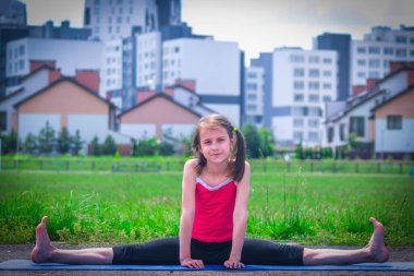 Genç sportif çekici kız ısınma egzersizi yapıyor ve bacaklarını açıyor. Kentsel koşullarda spor eğitimi. 
