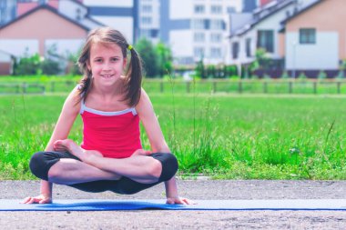 Mavi hasırda yoga yapan genç çekici kızın portresi bacak bacak bacak üstüne atarak kol dengesi egzersizi, Pul Duruşu, Tolasana, Utpluthi Poz, tam boy. Boşluğu kopyala.