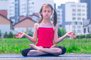 Yoga nilüferinde oturan genç bir kızın portresi, şehrin süper hızlı temposundaki sağduyu ve zihin huzurunun korunmasının sembolü olarak şehrin arka planında poz veriyor.