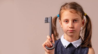 Kavramsal görüntü: cevaplara ihtiyacımız var! Büyük anahtarı elinde tutan genç kızın psikolojik portresi cevaplar ve kendini kabullenme arayışının sembolü.. 