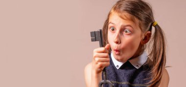 Şaşırmış genç bir kızın komik psikolojik portresi. Cevapları aramanın sembolü olarak elinde büyük bir anahtar tutuyor. Metin veya tasarım için boşluk kopyala.