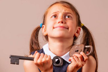 Kafası karışmış genç bir kız elinde büyük anahtar ve küçük bir kilit tutuyor. Kötü şifrenin, güvenliğin ve şifre yönetiminin sembolü olarak.. 