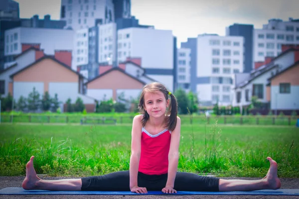 Genç sportif çekici kız ısınma egzersizi yapıyor ve bacaklarını açıyor. Kentsel koşullarda spor eğitimi. 