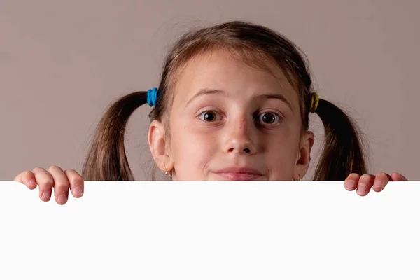 在白色空白横幅或棕色背景的空白复制空间广告板后面的可爱的年轻女孩滑稽的肖像 复制文字或设计的空间 横向图像 — 图库照片